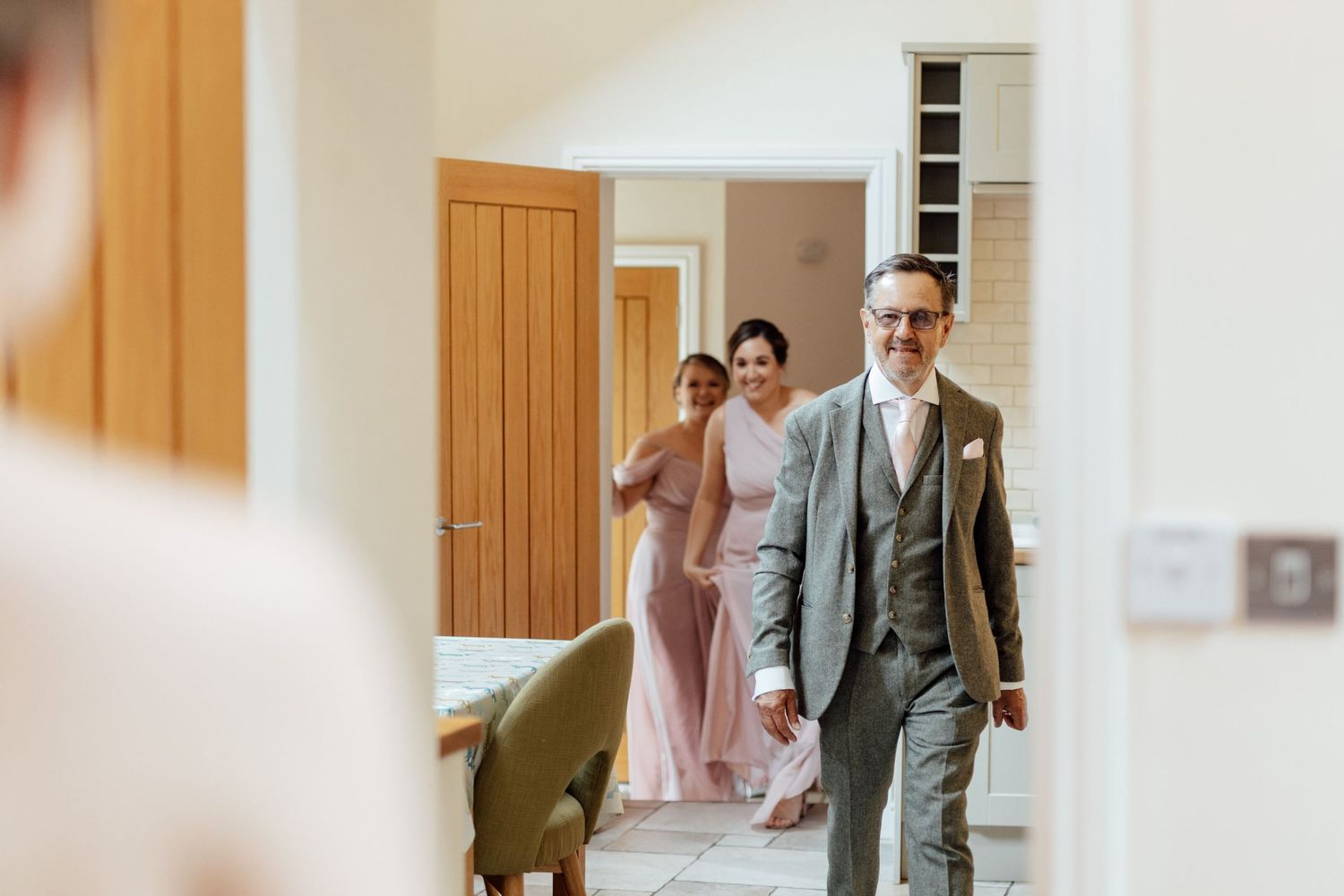 Wedding party members walking through a bright hallway with wooden paneling.