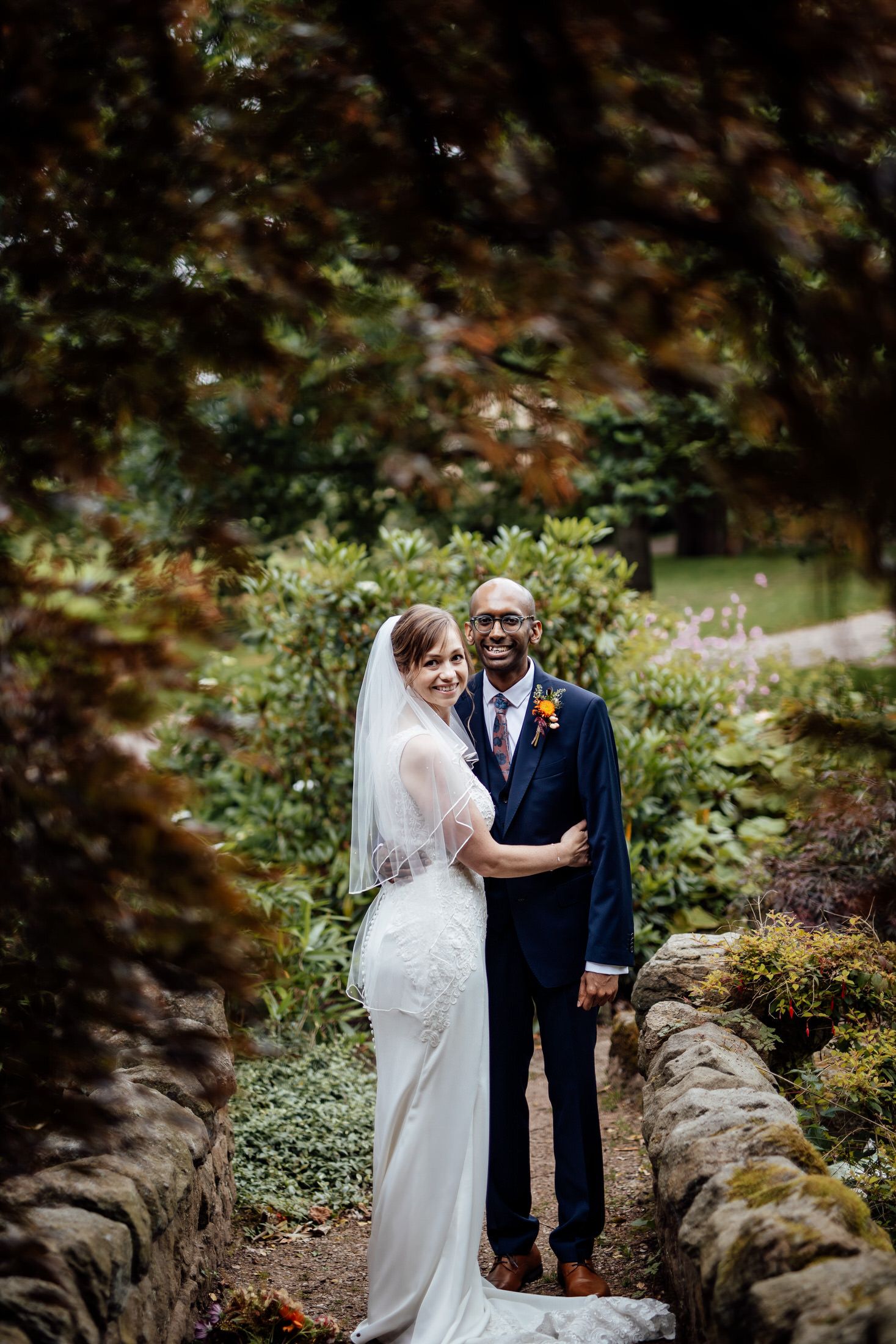 Romantic wedding portraits captured in a lush garden setting with natural stone features.