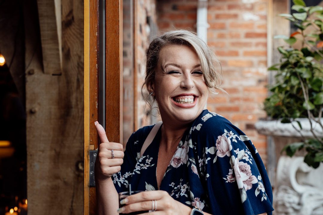 Candid reception moments captured against rustic brick wall interior.