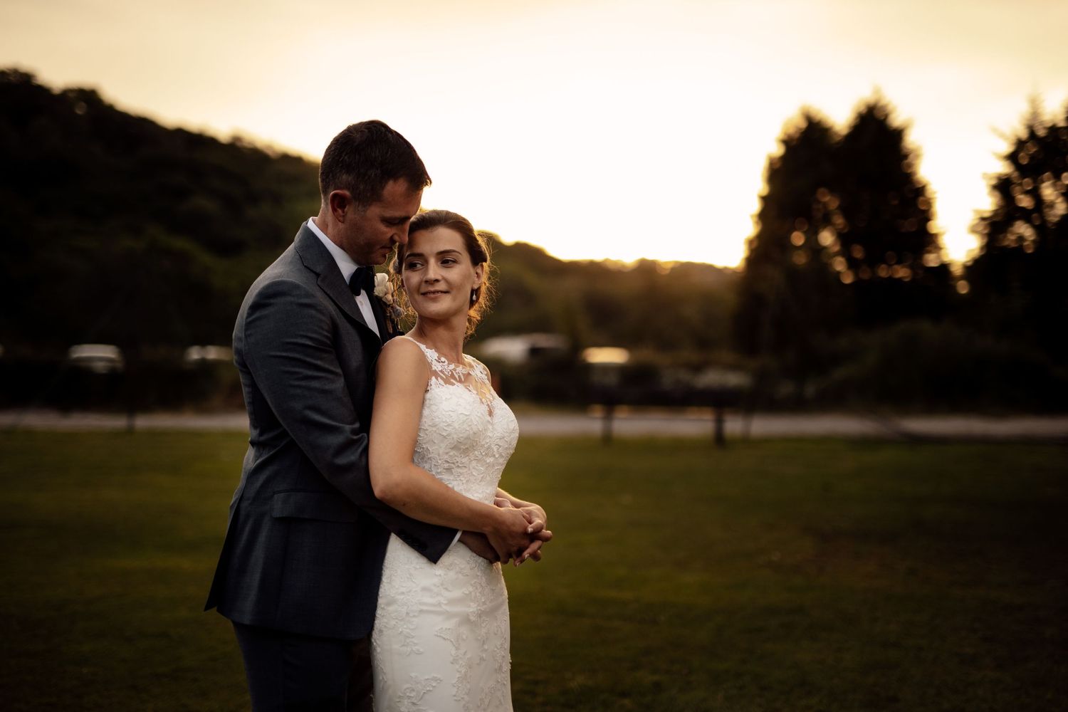 A romantic sunset wedding portrait captured in a golden field during magic hour.