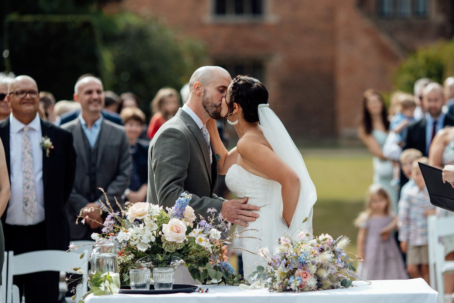 Outdoor wedding ceremony with floral arrangements and guests in attendance.