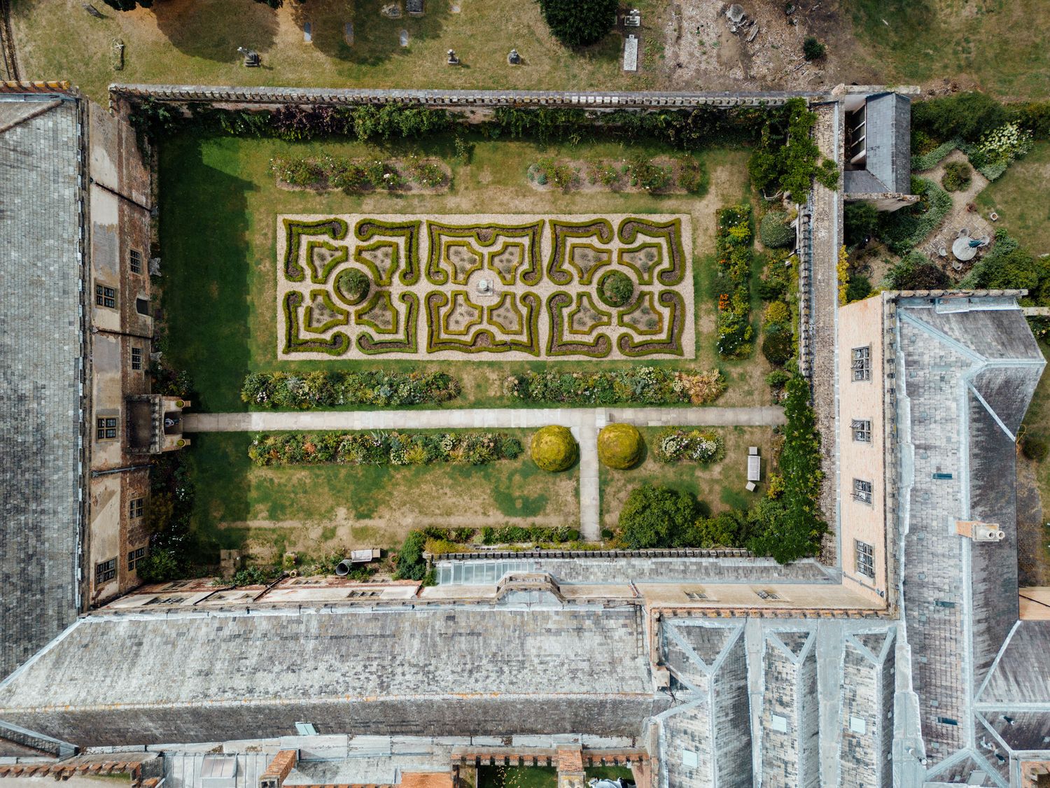 Aerial view of formal gardens with geometric patterns and stone pathways.