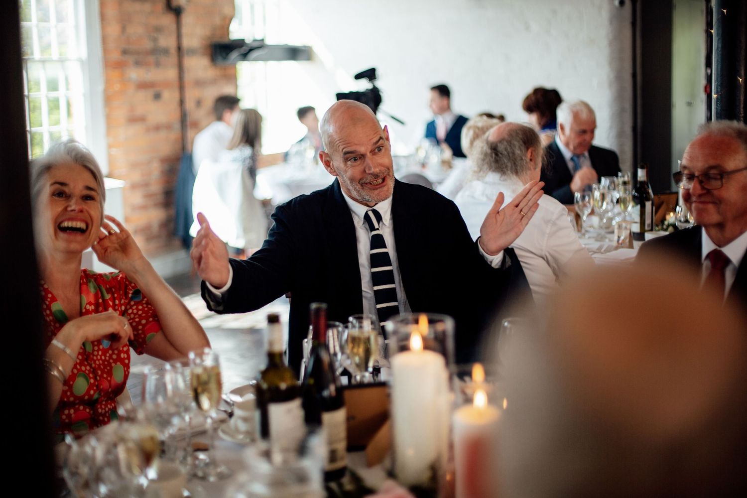 Wedding guests enjoying conversation and laughter during indoor reception.