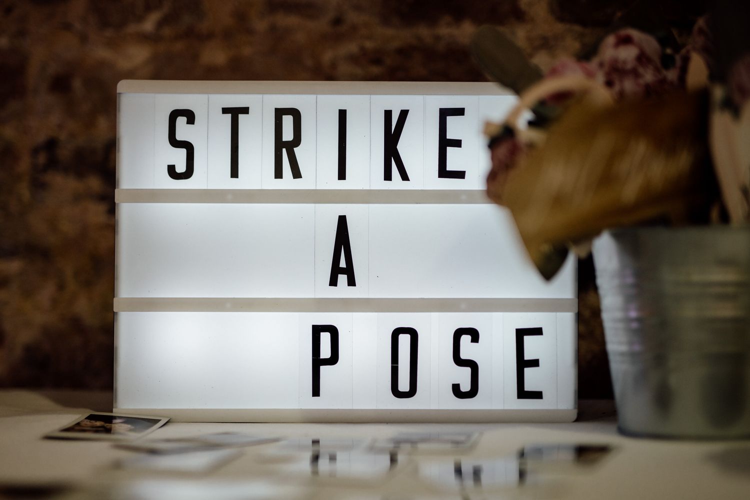 Illuminated lightbox sign displaying 'STRIKE A POSE' text against dark background.