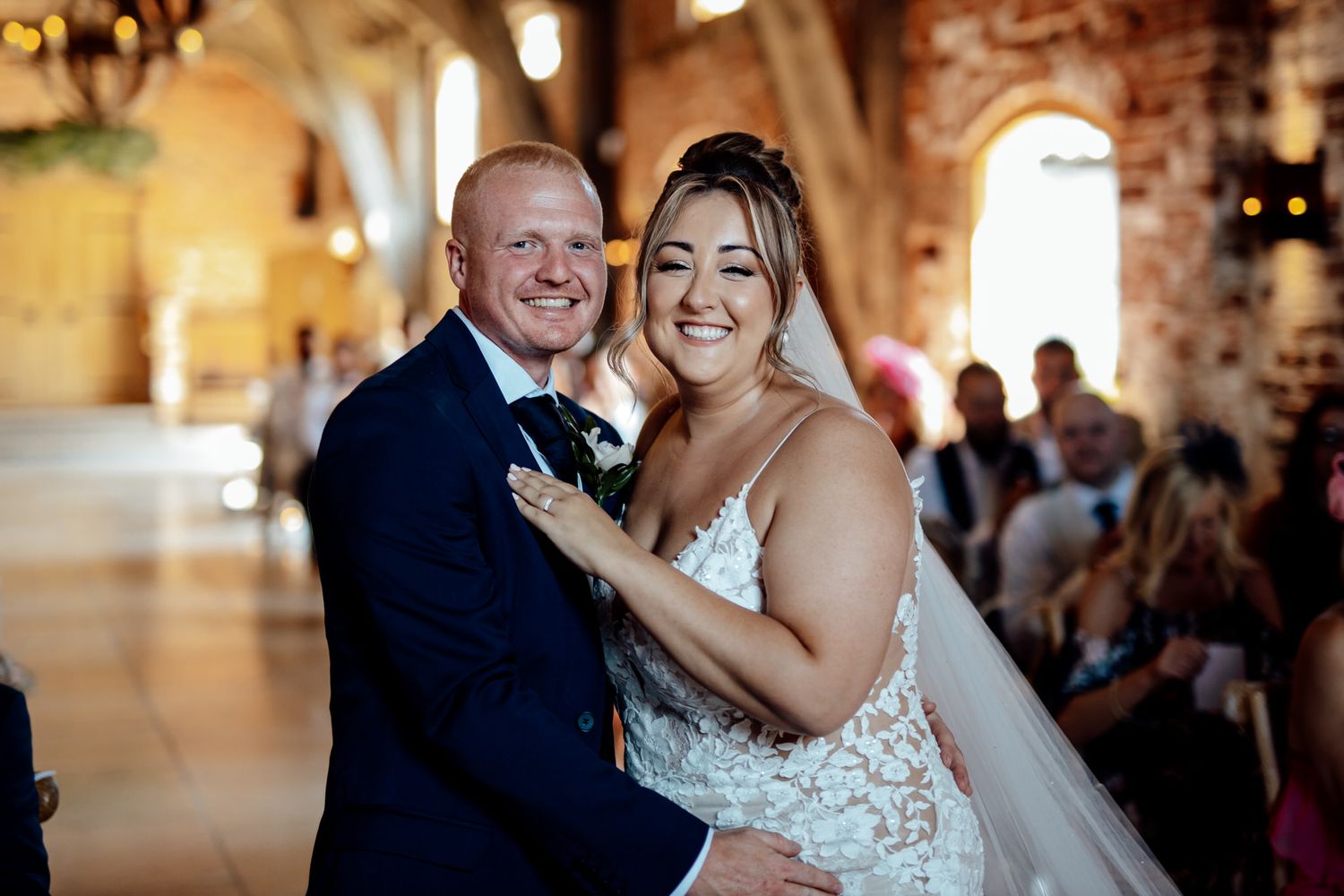 Happy couple shares intimate dance moments during wedding reception in rustic brick venue.