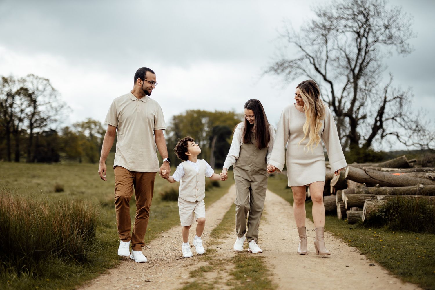 A family holds hands while walking together on a dirt path surrounded by nature.
