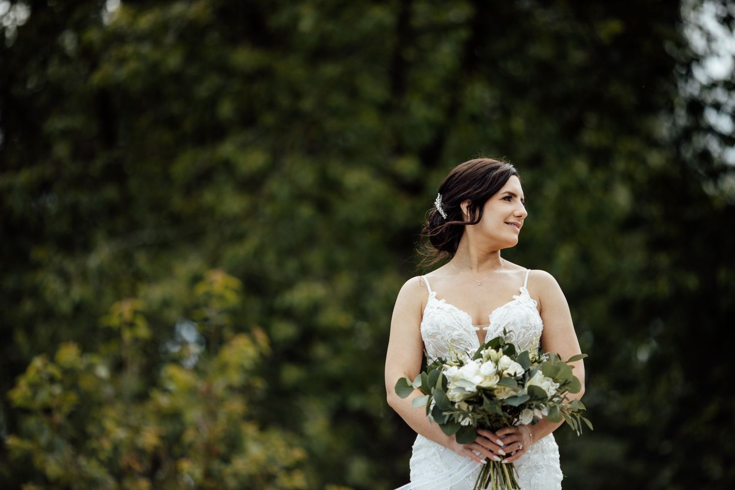 White bouquet and wedding shoes arranged on dark surface with dramatic lighting.