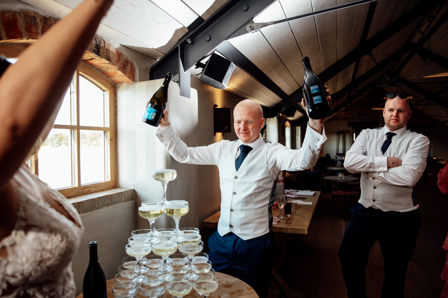 Champagne tower being carefully filled at elegant wedding reception.