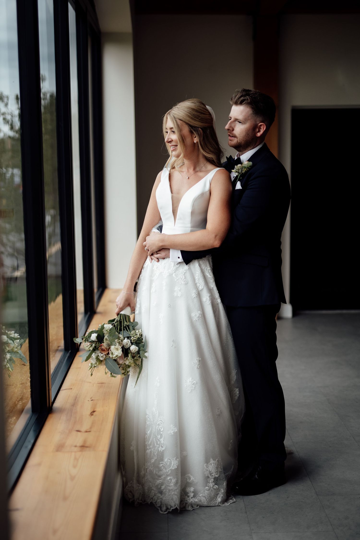 Elegant bride and groom share intimate moments in a modern venue with natural lighting.