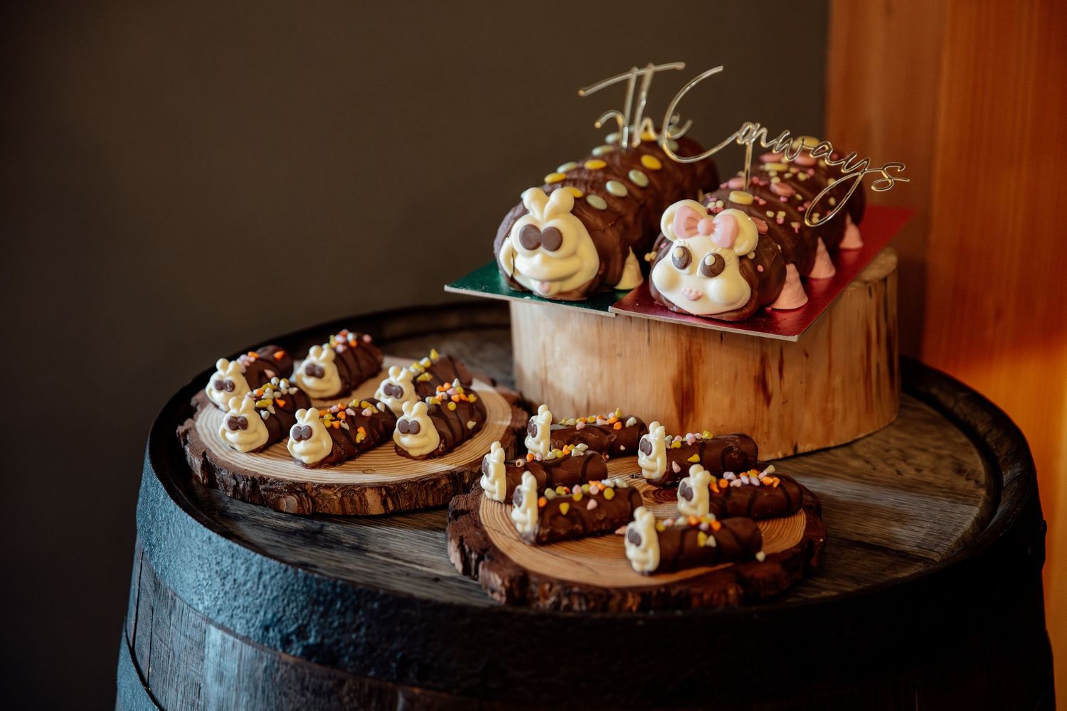 Assorted chocolate desserts and treats displayed on rustic wooden barrels.