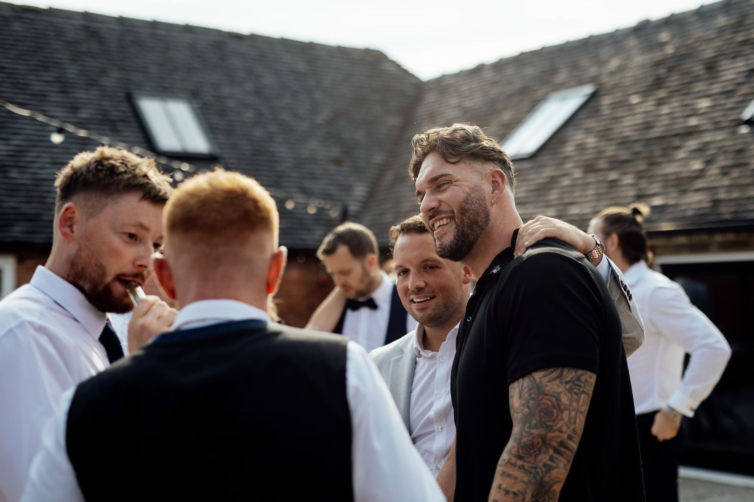 Wedding guests laugh and celebrate during an outdoor reception gathering.