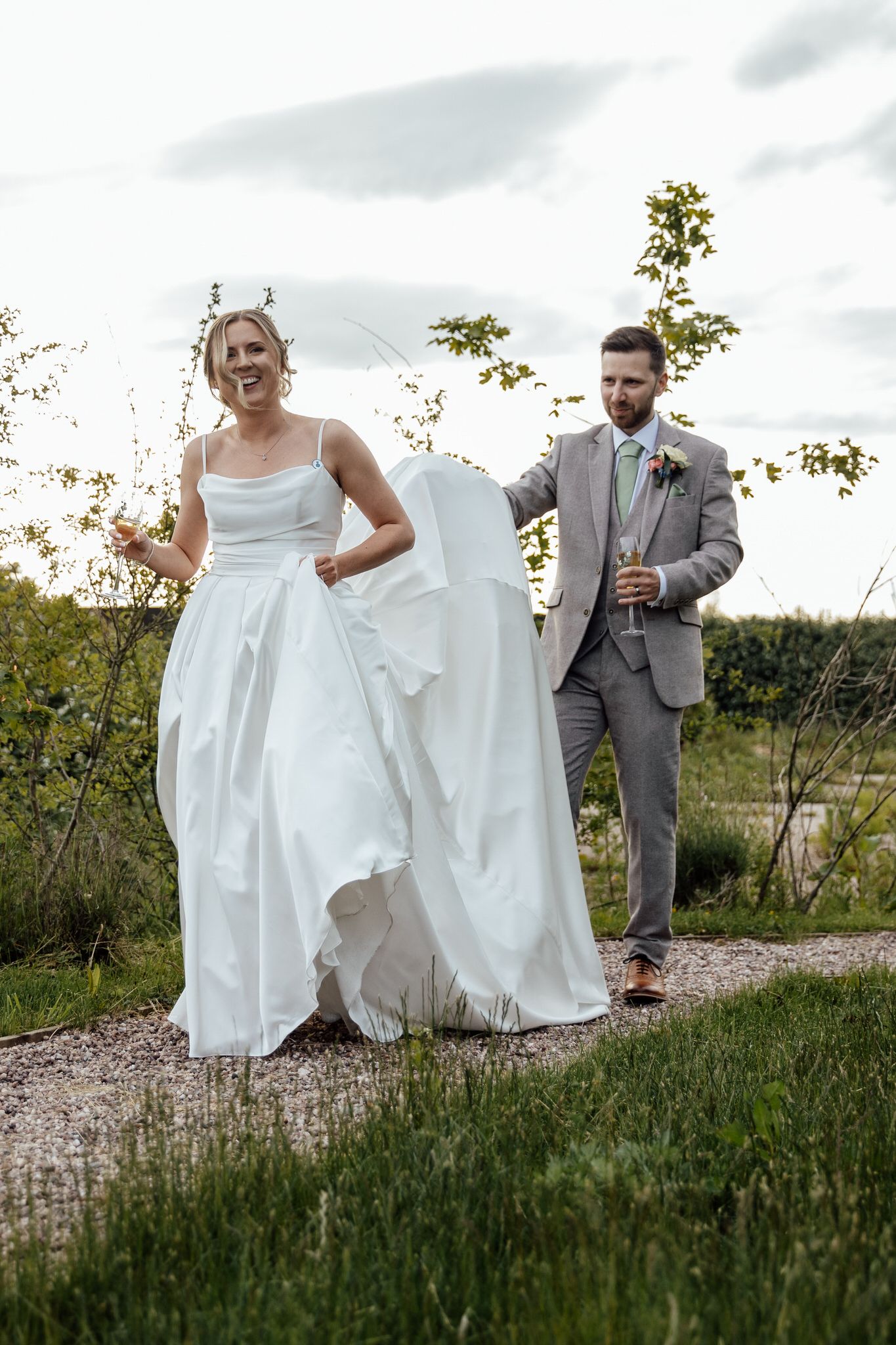 Wedding party walking and laughing together on a gravel path outdoors.
