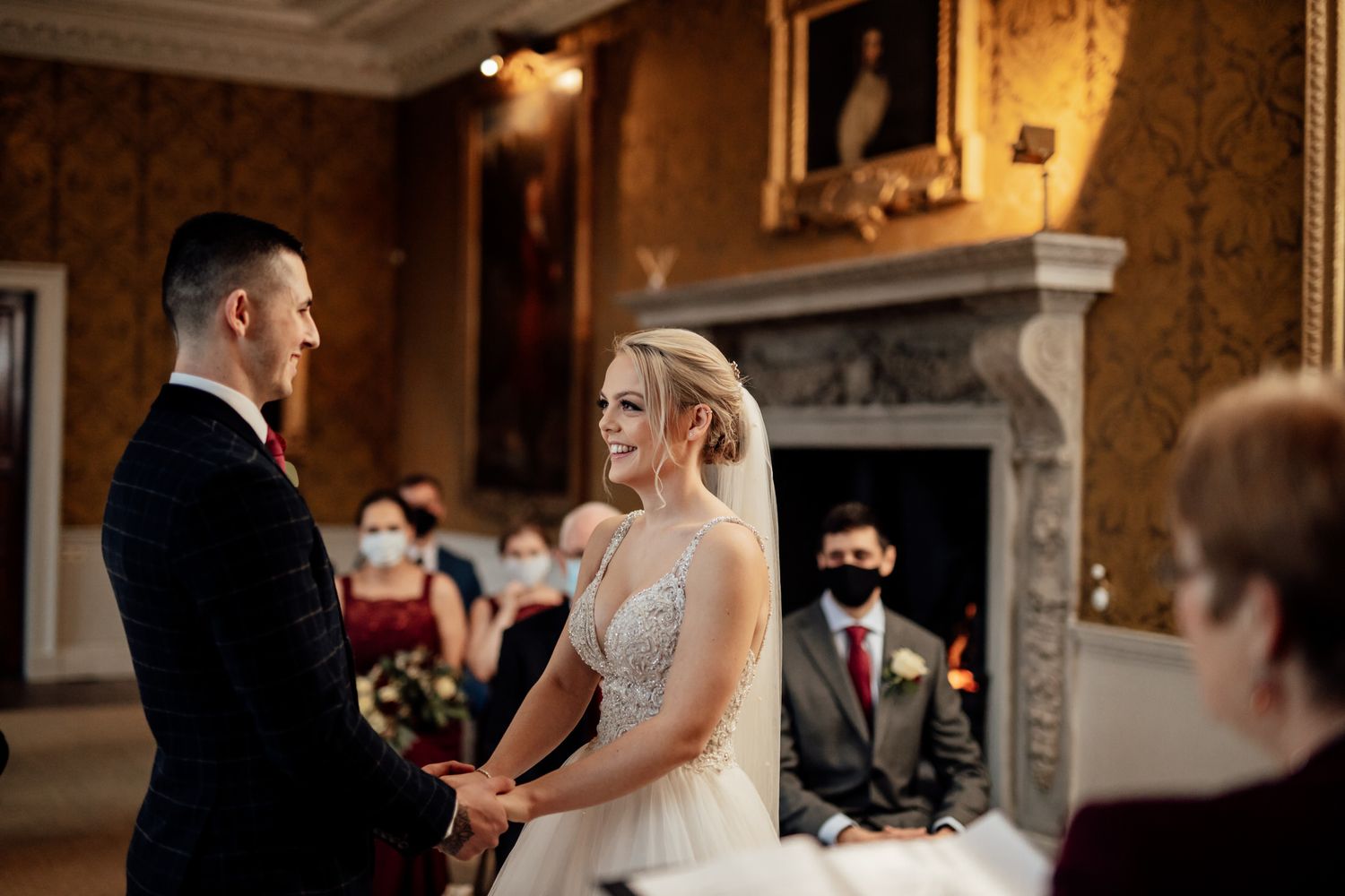 Elegant wedding ceremony in a grand historic room with ornate architectural details and warm lighting.