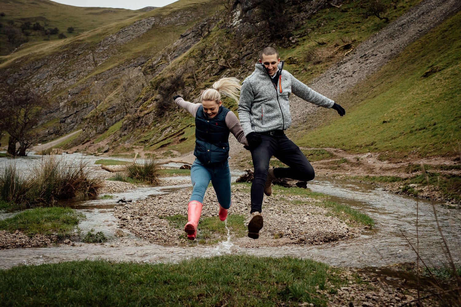 Adventurous couple explores rocky terrain in a mountainous landscape.