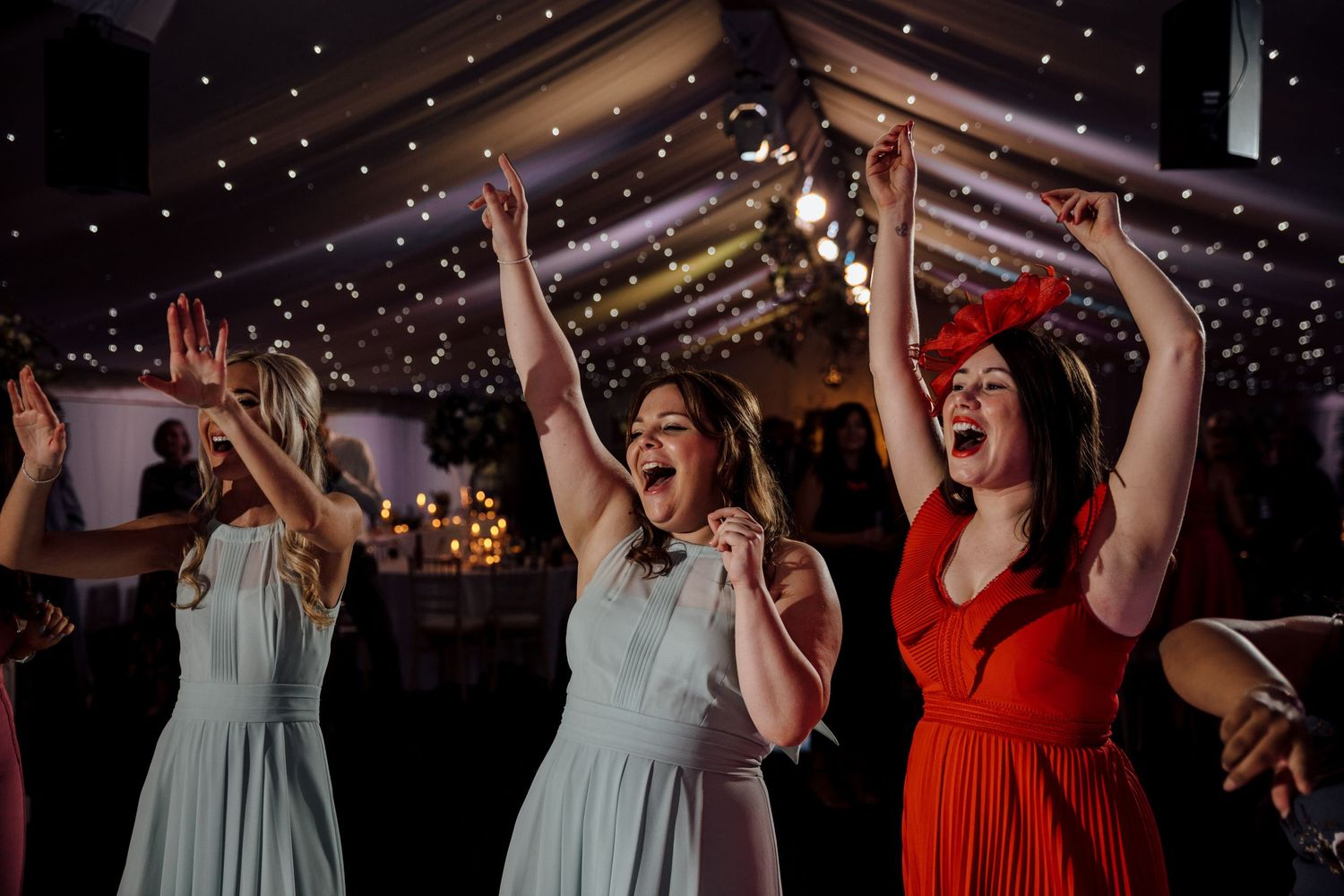 Wedding party dancing and celebrating on a festive dance floor with dramatic lighting and decorations.