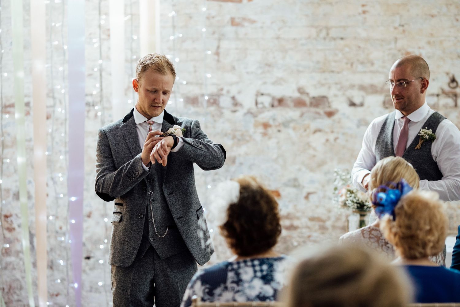 Wedding guests mingling and socializing in an industrial-style venue with exposed brick walls.