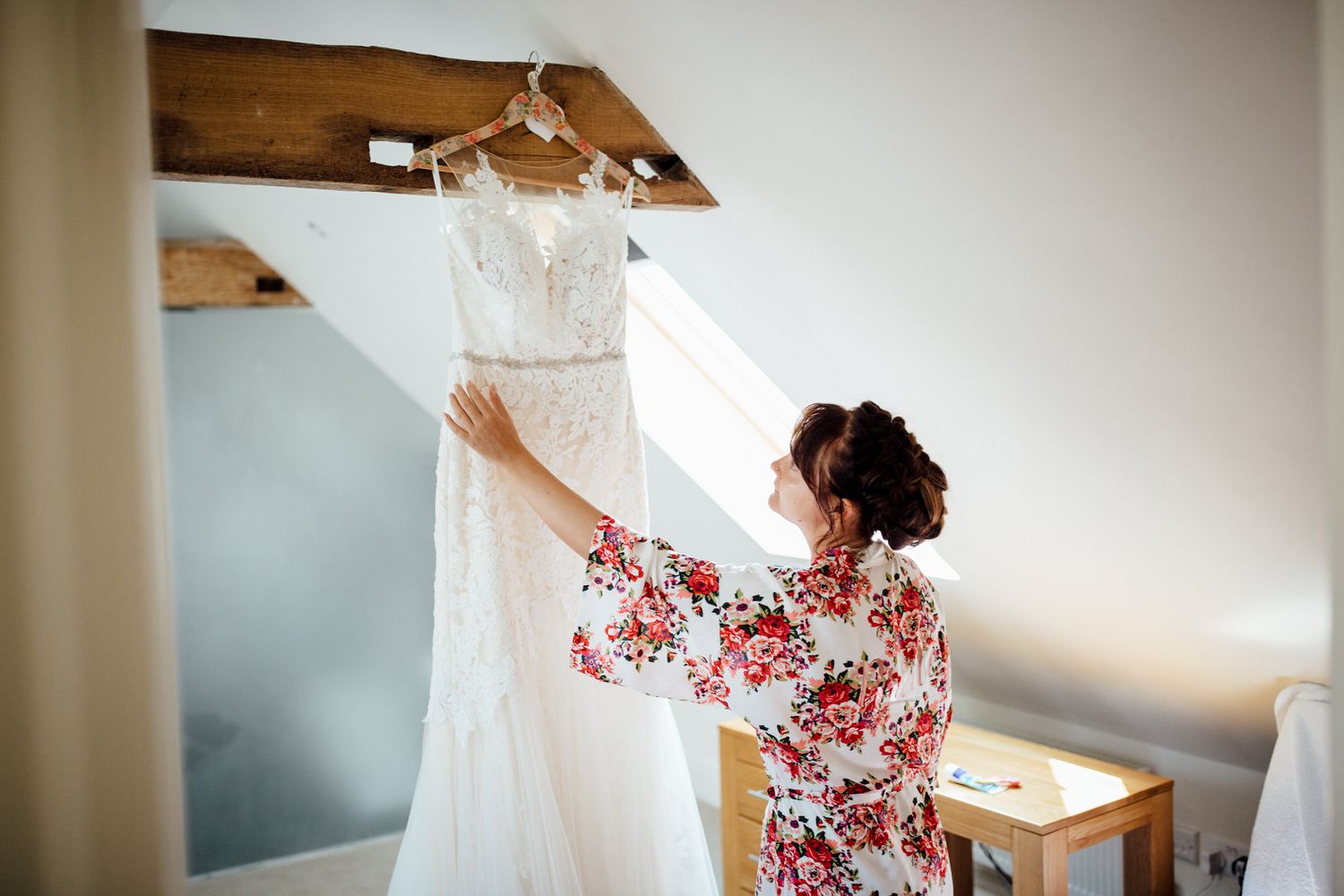 White wedding dress being displayed in natural window light at rustic venue.