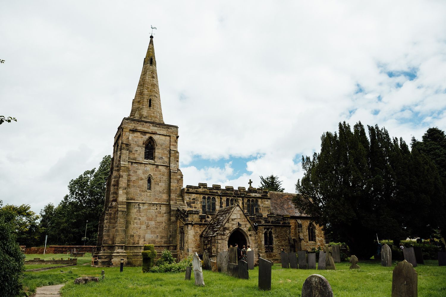 Historic stone church and cemetery grounds under cloudy sky.