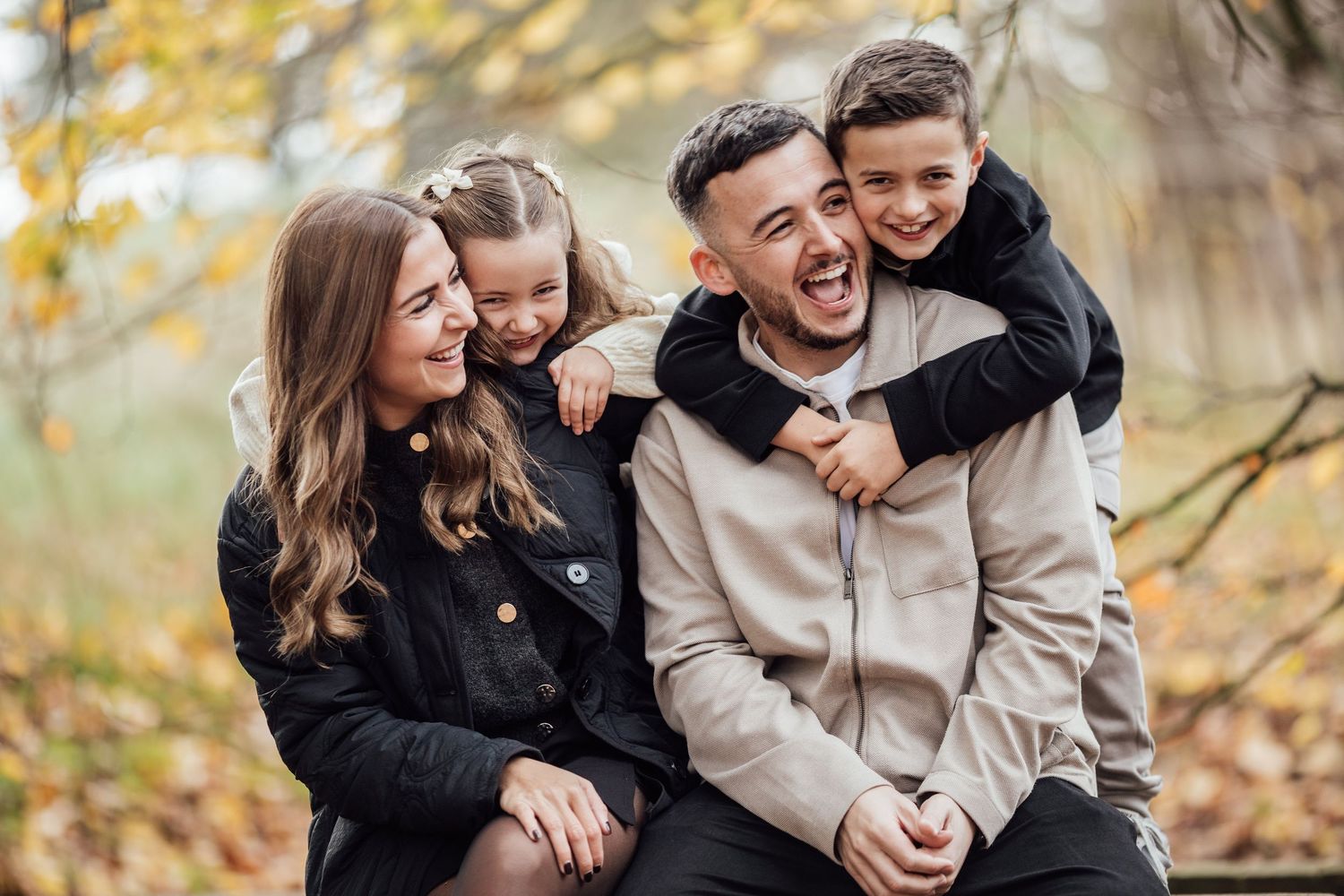 Family enjoying playful moments together outdoors during fall season.