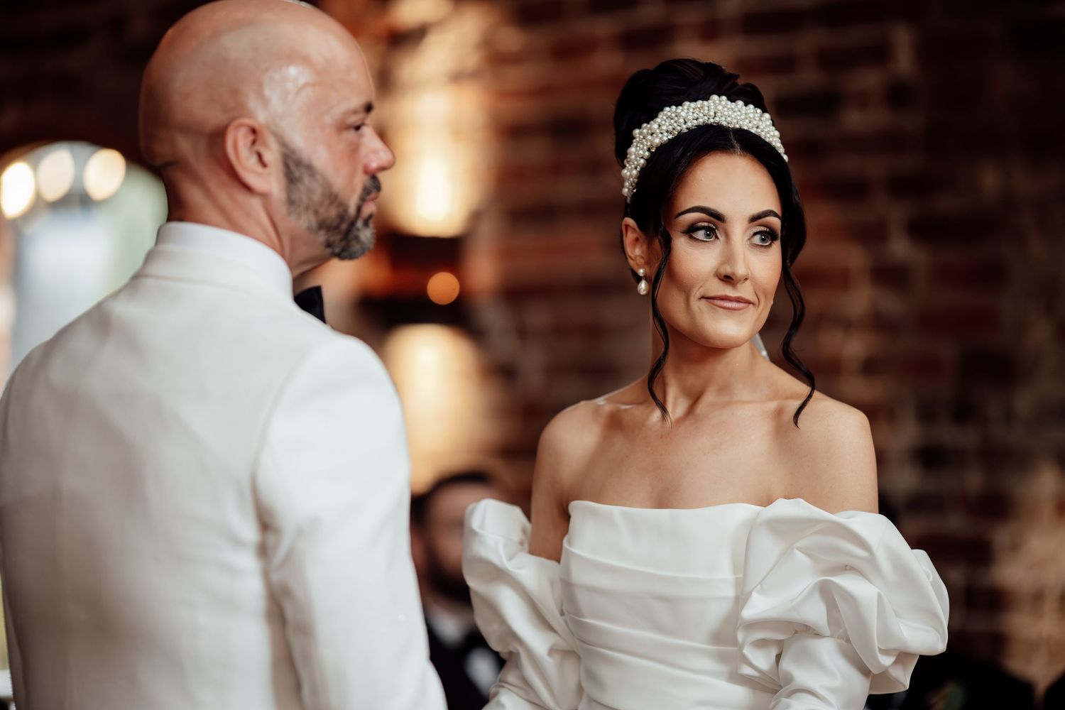 Romantic wedding couple sharing an intimate moment in front of exposed brick walls.