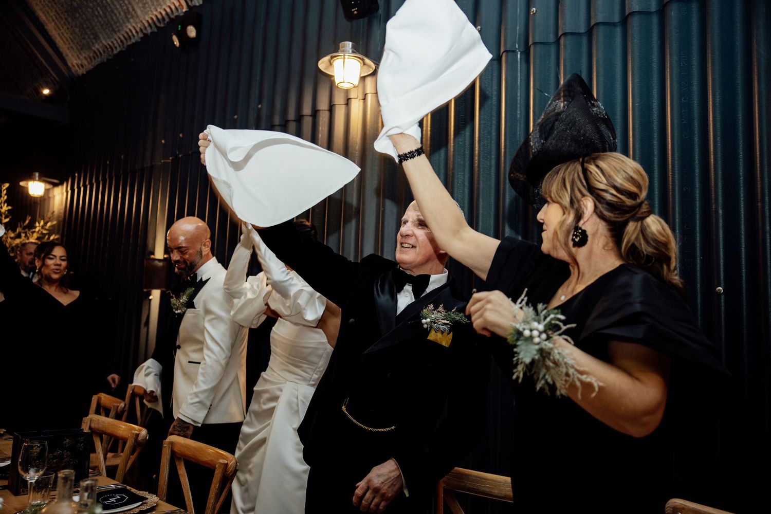 Wedding guests wave napkins during a celebratory moment at the reception.