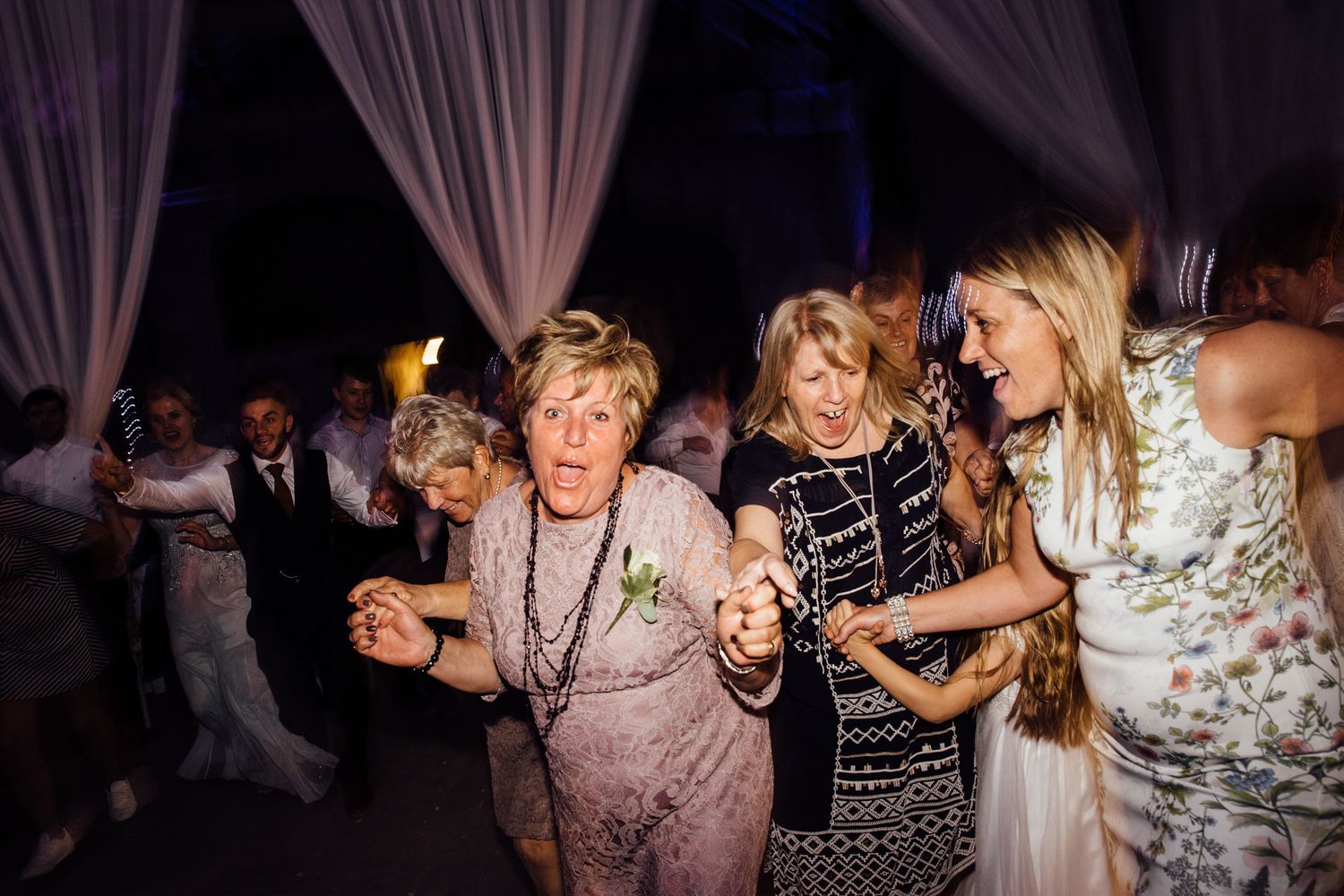 Guests enjoying themselves on a dimly lit dance floor at an evening wedding reception.