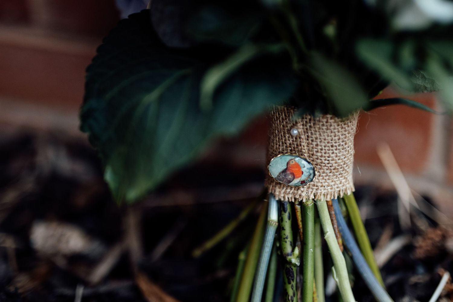 A wedding bouquet detail showing a sentimental photo charm wrapped in burlap.