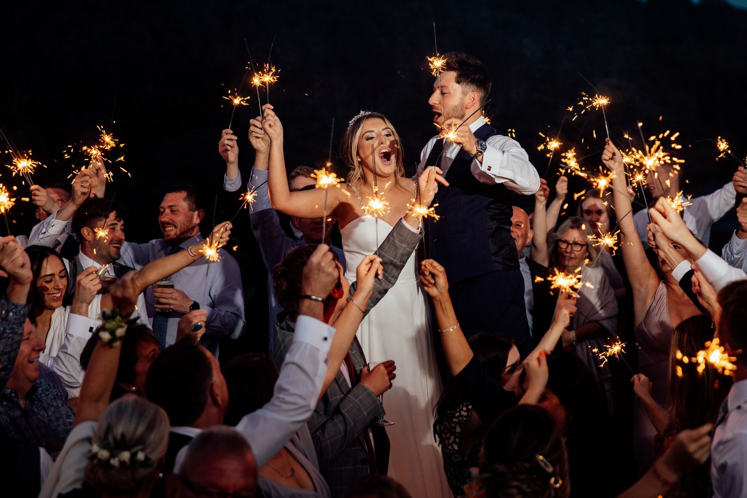 Wedding celebration at night with sparklers creating a magical atmosphere on the dance floor.