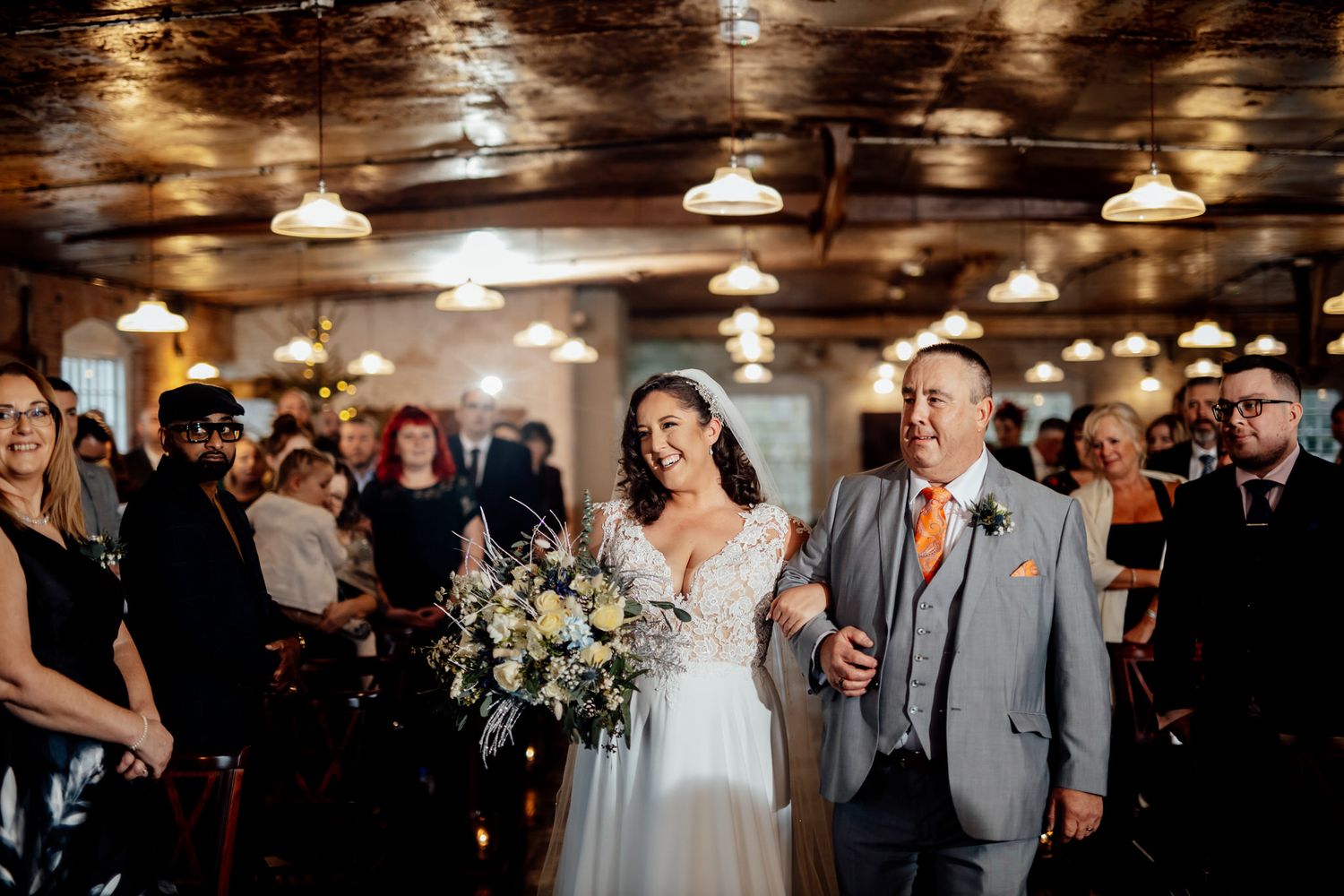 Wedding party celebration in a rustic venue with warm ambient lighting.