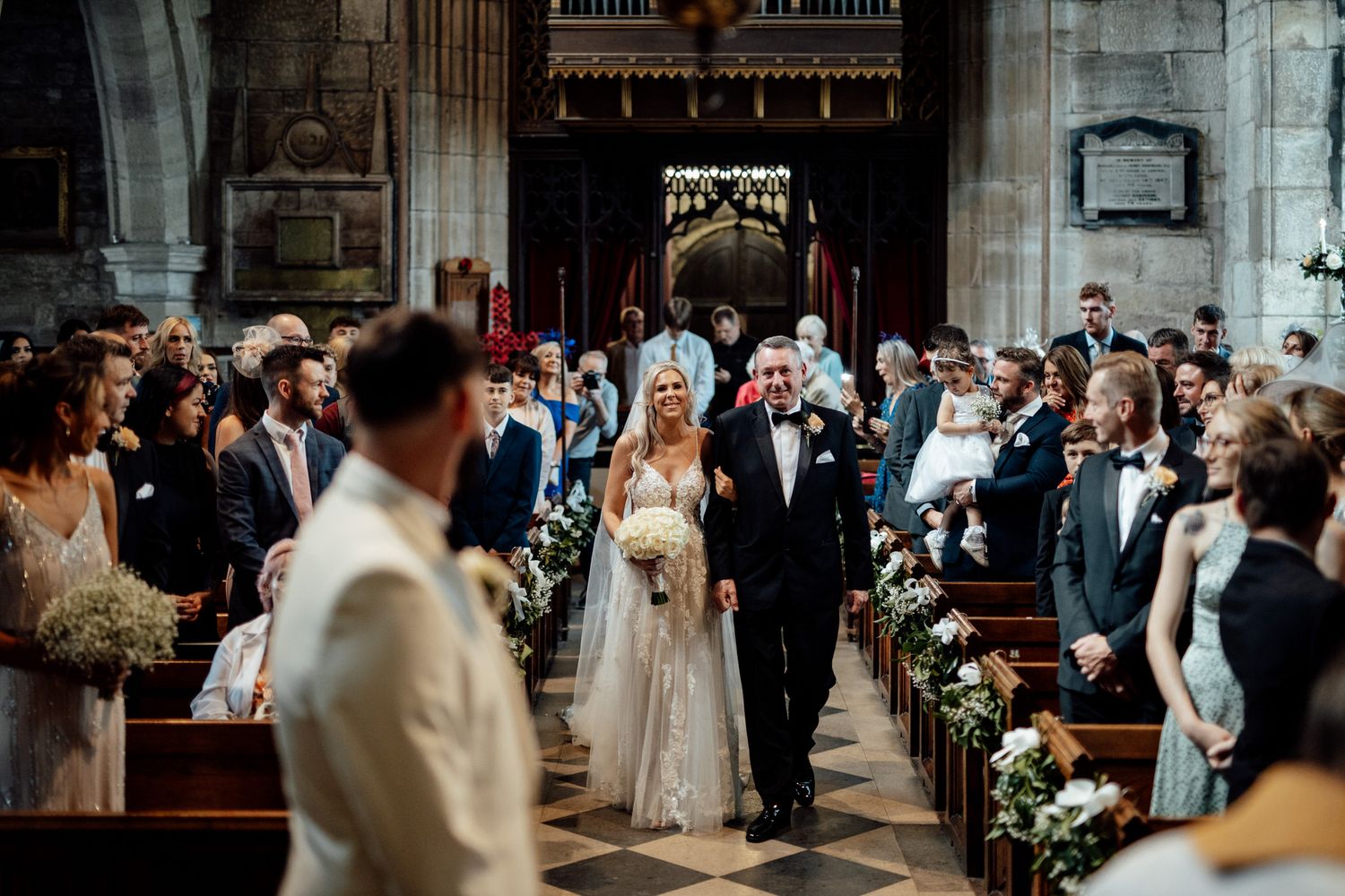 Wedding ceremony in grand cathedral with stone columns and stained glass windows.