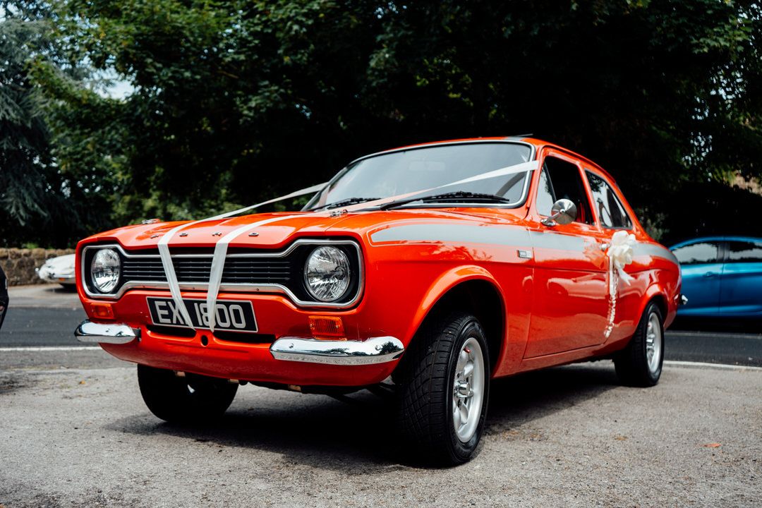 Vintage bright red Ford Escort classic car parked outdoors.