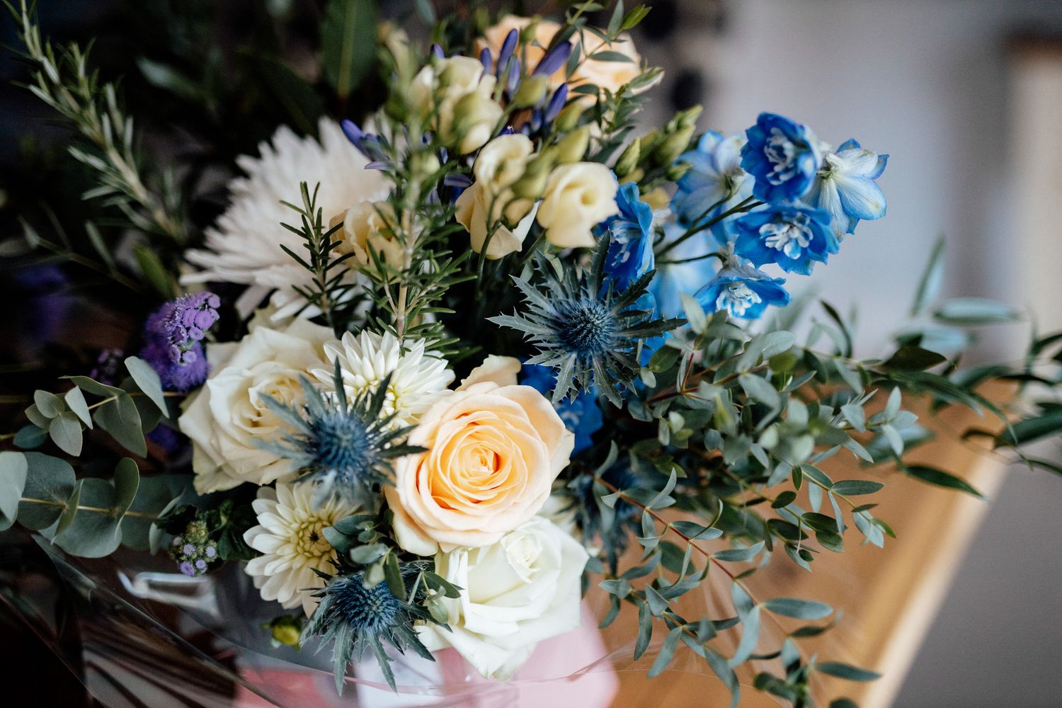 Delicate floral arrangements featuring peach roses and blue accents on display.