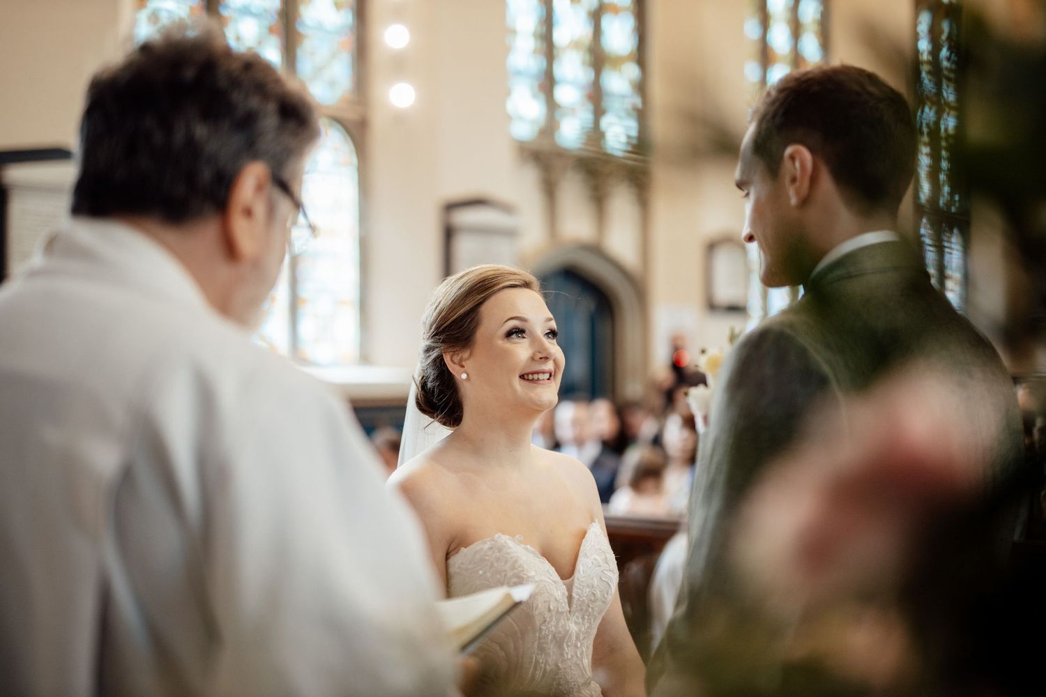 Wedding guests laugh and celebrate during an indoor reception with warm lighting and festive atmosphere.