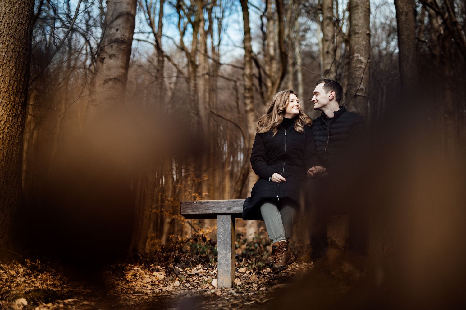 A couple shares an intimate moment while walking through a misty winter forest path.