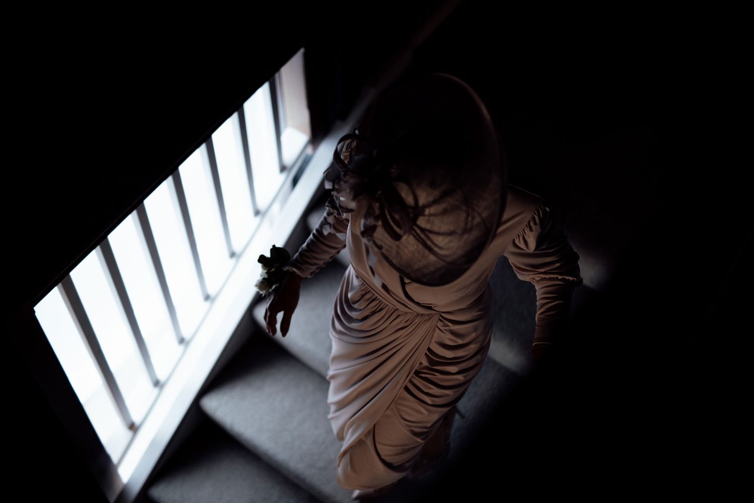 Artistic overhead shot of someone sitting by a window in dramatic lighting.