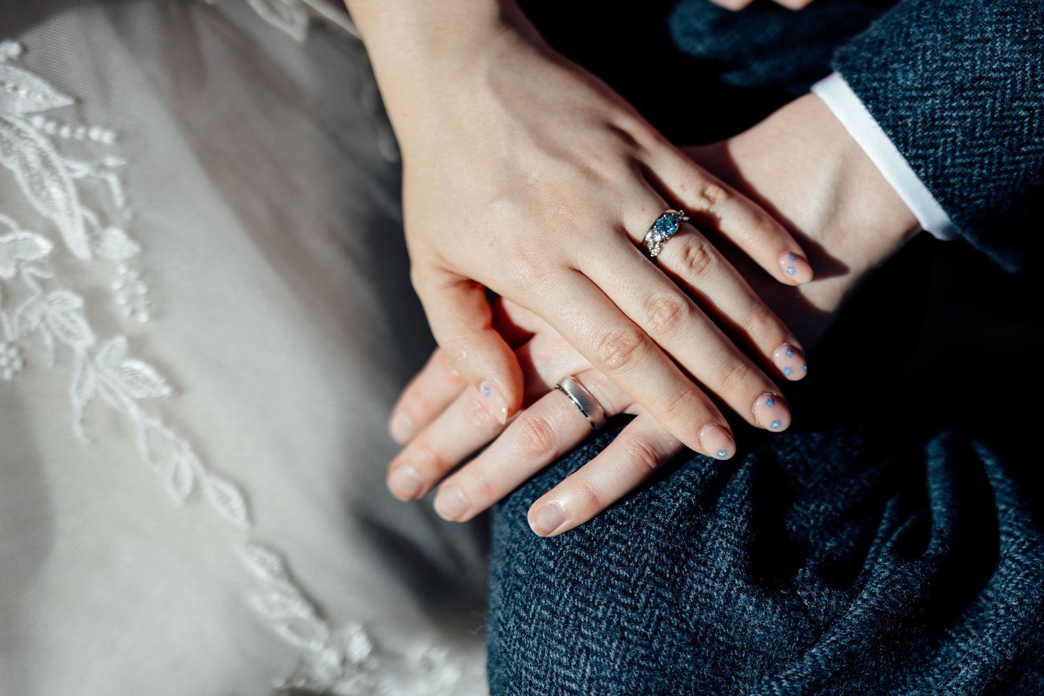 Close-up detail shot of hands and rings at a formal event.