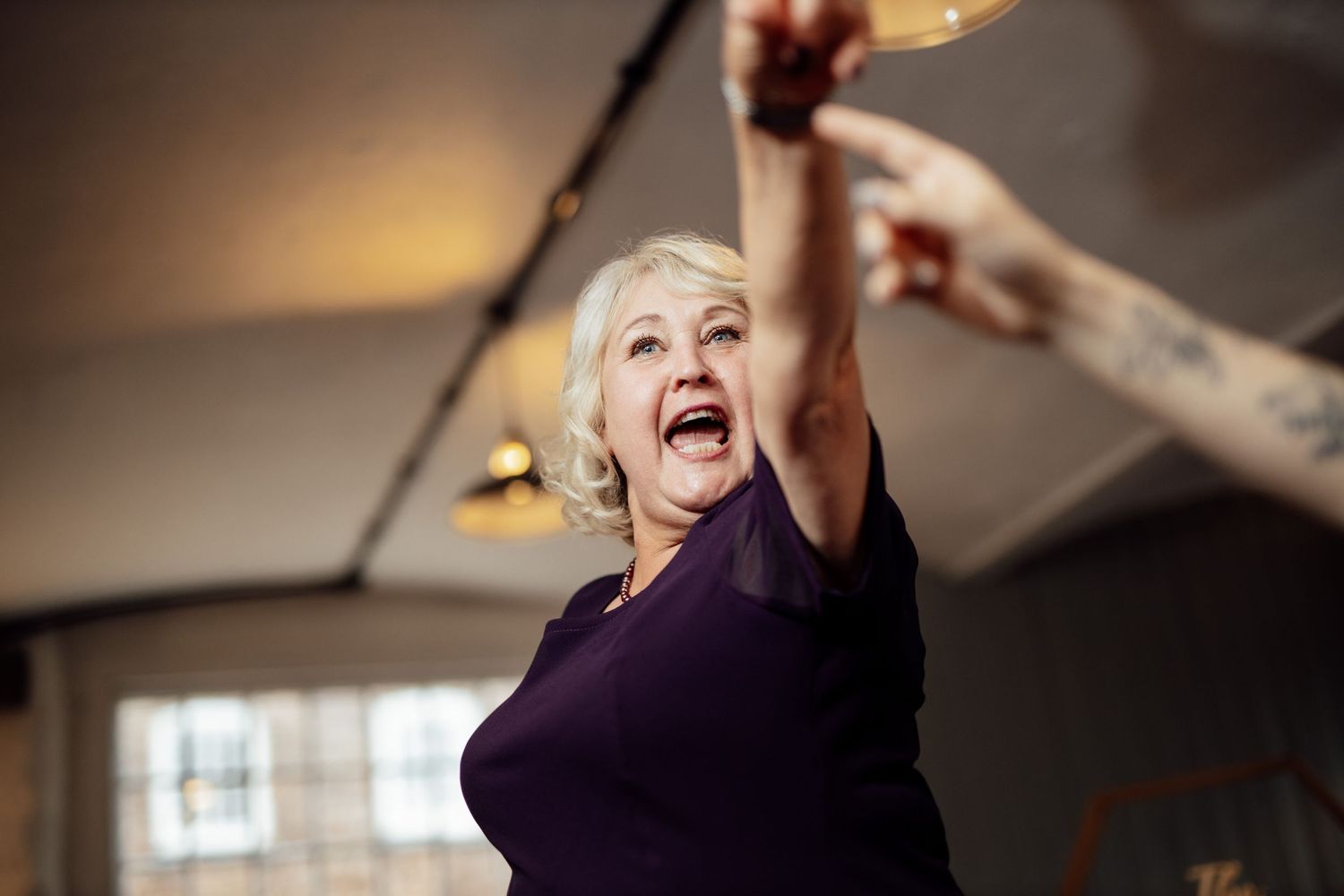 Wedding guests raise champagne glasses for a celebratory toast under warm lighting.