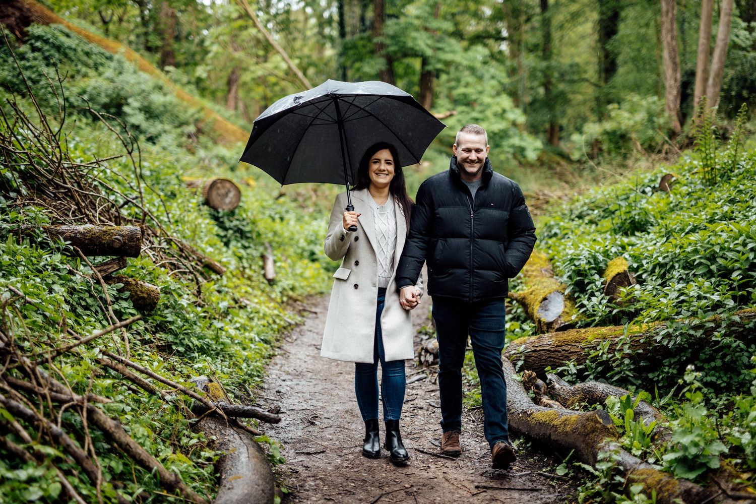 A group strolls along a winding forest path surrounded by green foliage.