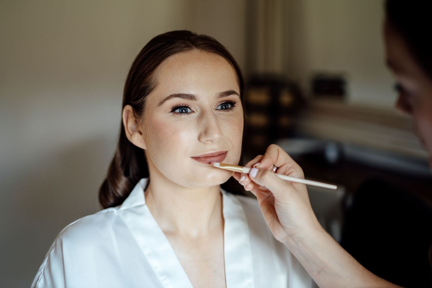 Getting ready scene with makeup artist applying cosmetics before the wedding.
