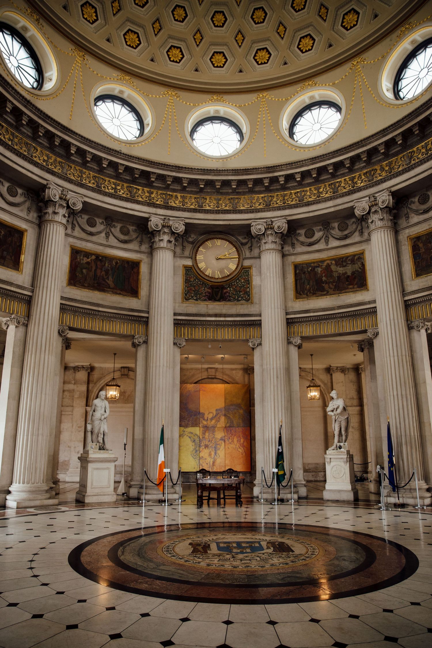 Ornate circular hall with classical columns and domed ceiling featuring geometric patterns.
