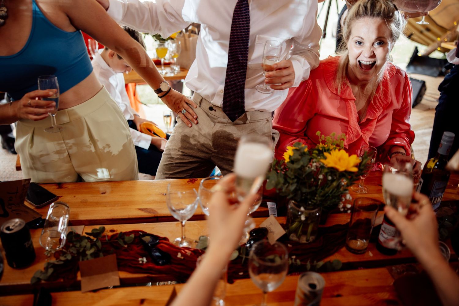 Wedding reception table with guests raising glasses for a celebratory toast.