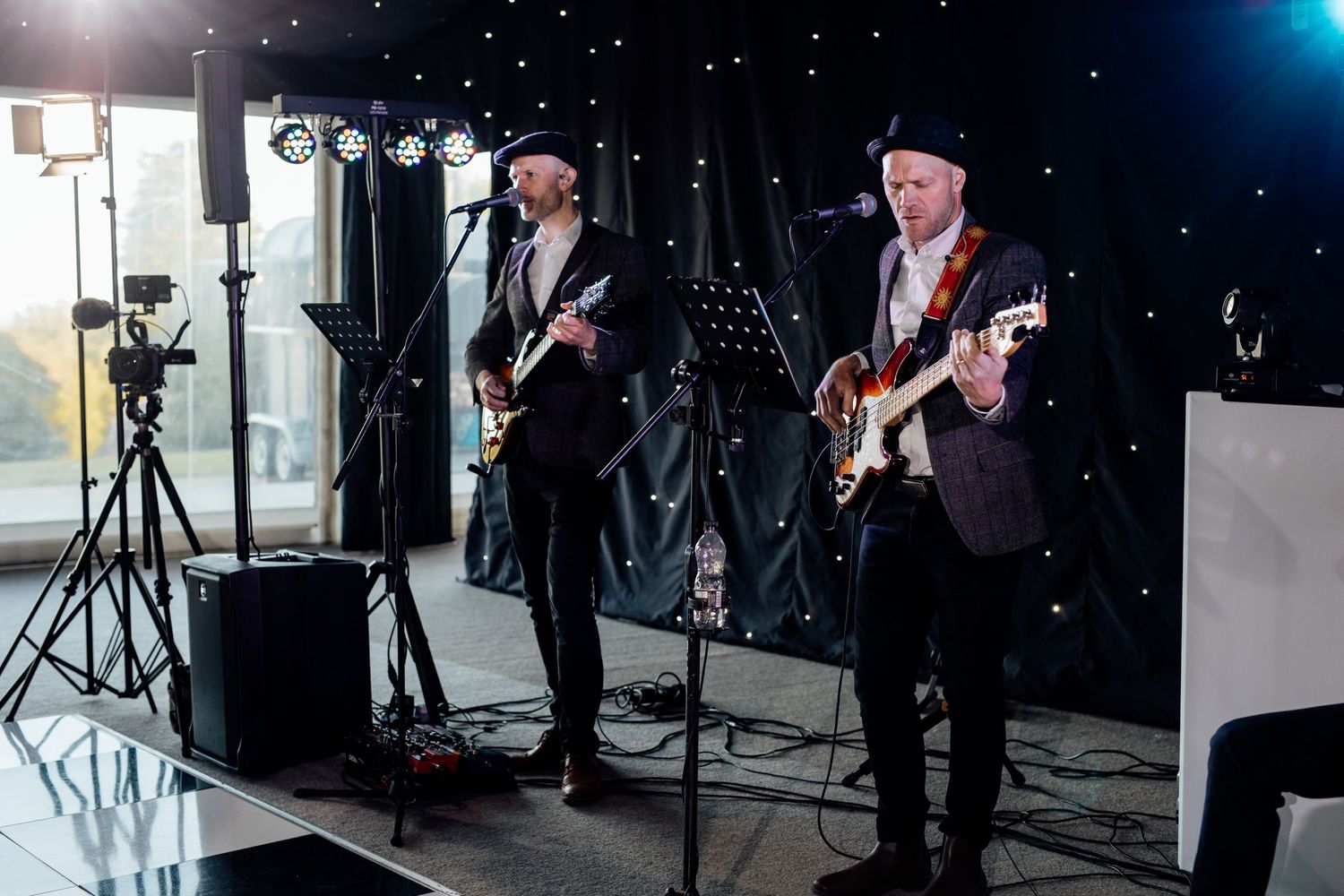 Band performing on stage with guitars under blue lighting at a wedding reception.