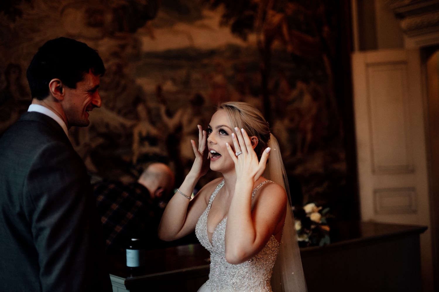 An emotional wedding moment captured in front of decorative wall murals.