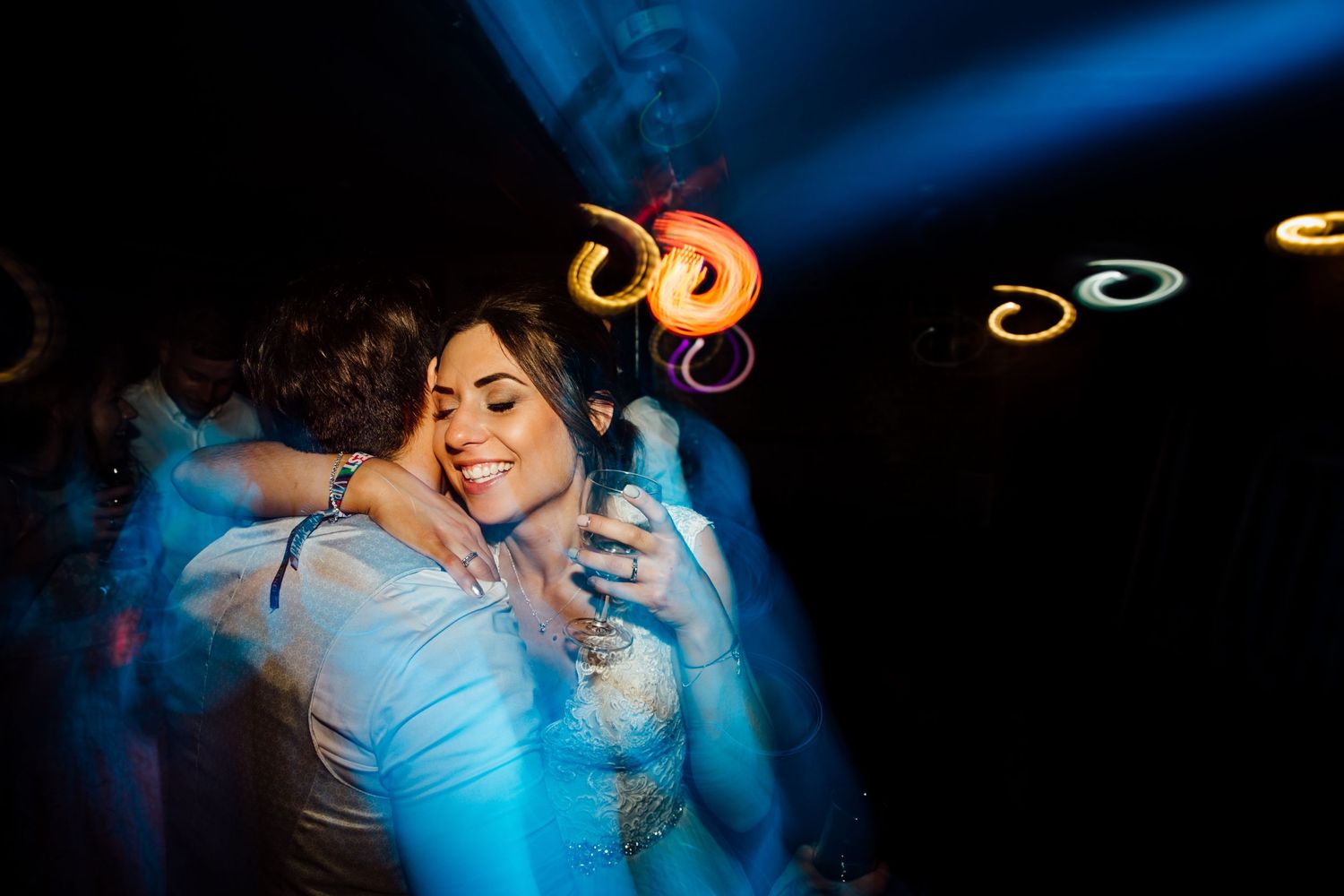 Romantic dance moment captured in blue spotlight at wedding reception.
