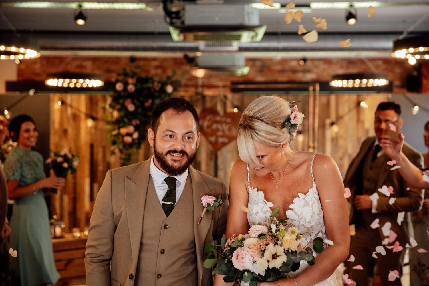 Wedding party celebrating at a rustic venue with exposed brick walls and warm lighting.