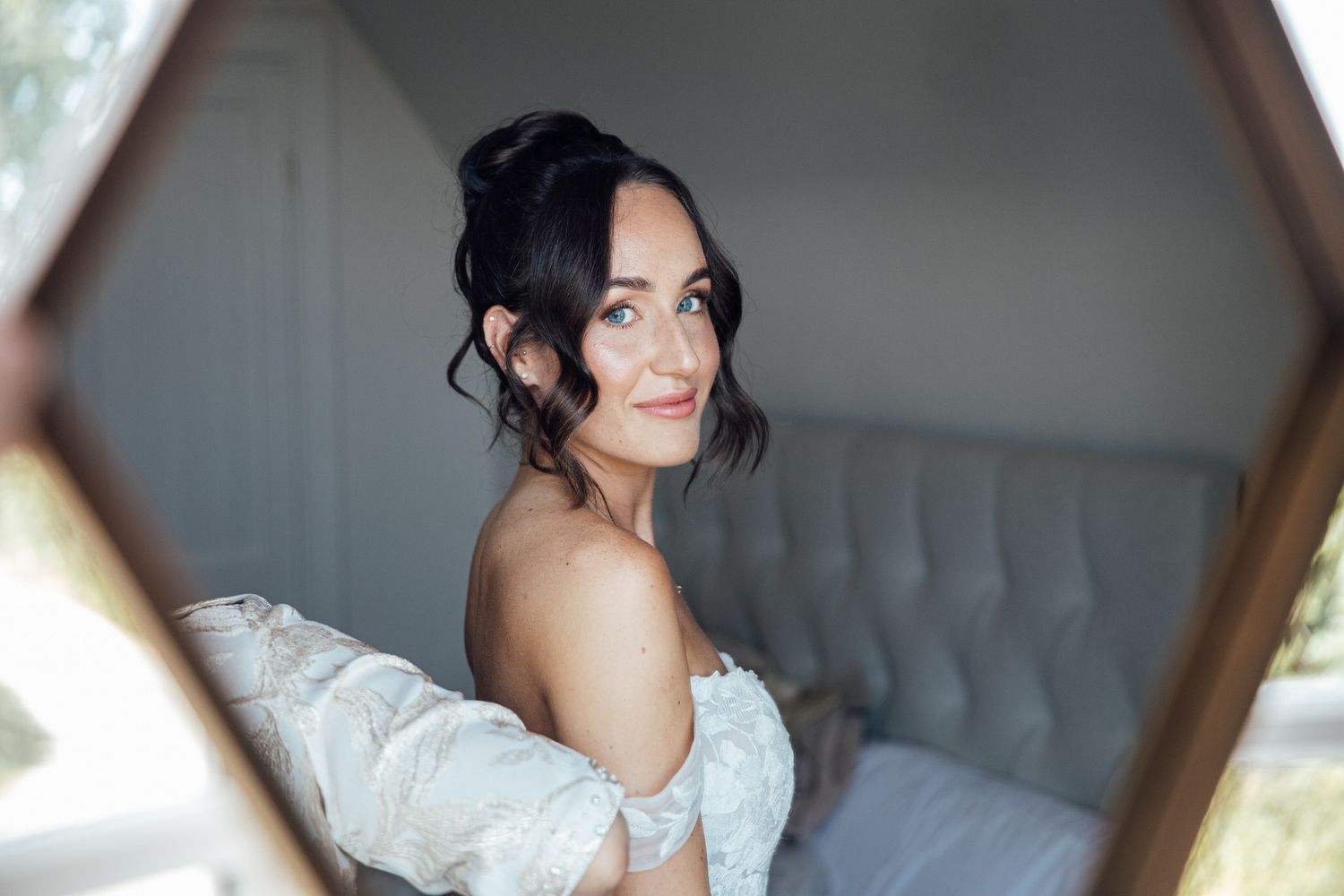 Elegant off-shoulder white wedding dress captured in a mirror reflection.