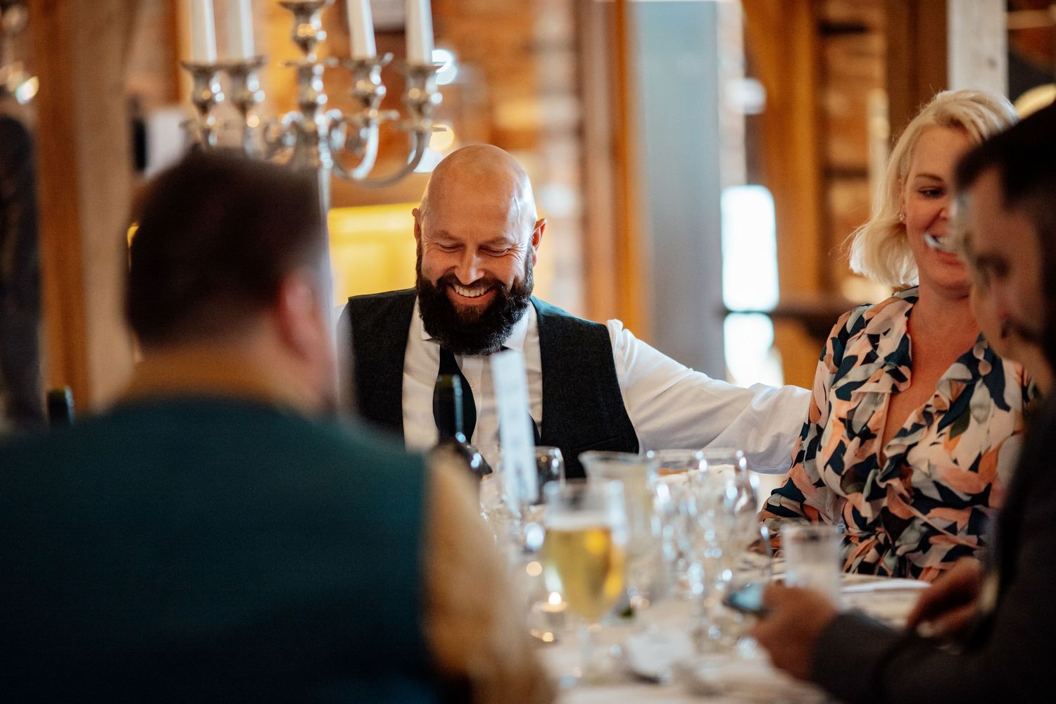 Guests enjoying drinks and conversation at an elegant indoor reception with chandeliers.