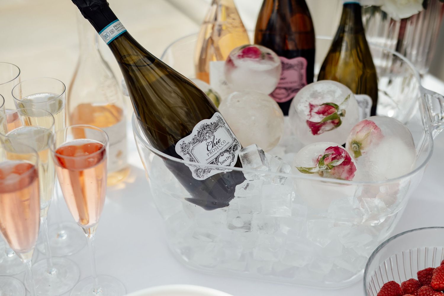 Wine glasses and champagne bottles arranged in ice at an elegant event.