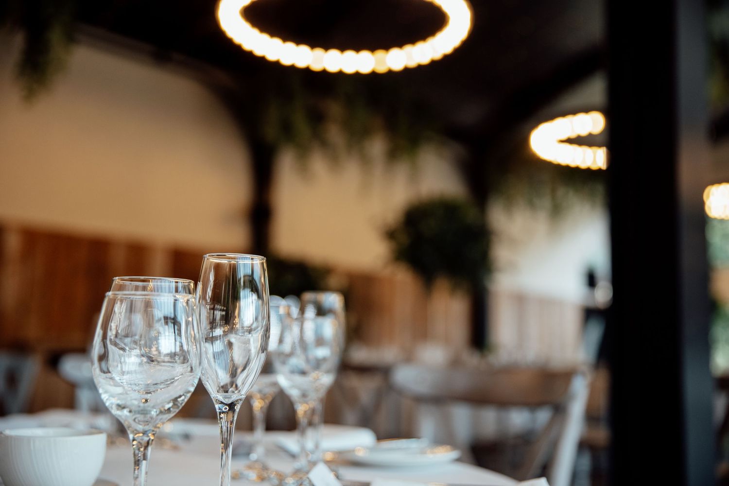 Elegant table settings with wine glasses and greenery decor at a wedding reception.