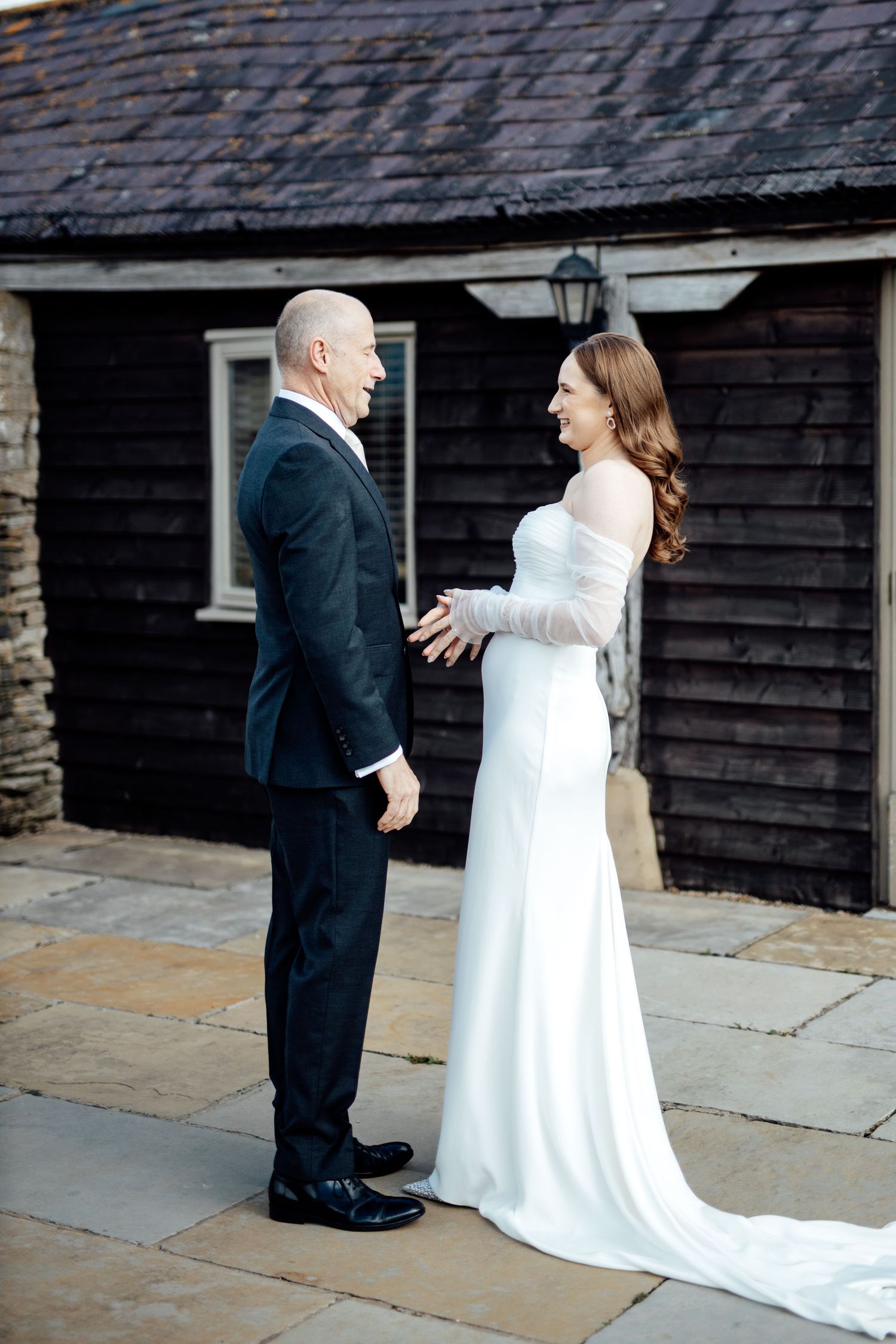 First look moment captured between couple outside rustic wooden building.
